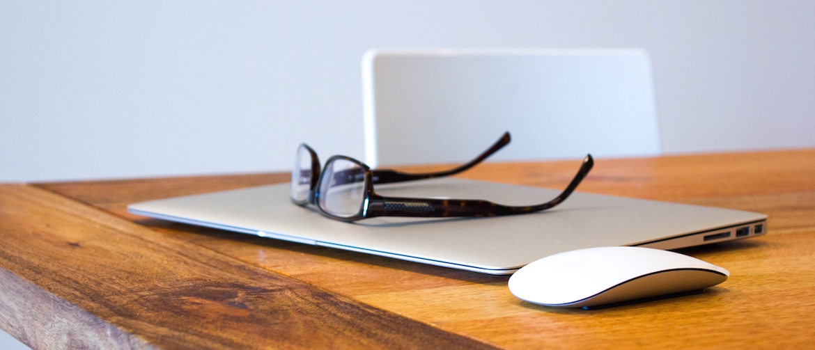 A desk with a laptop with classes on top